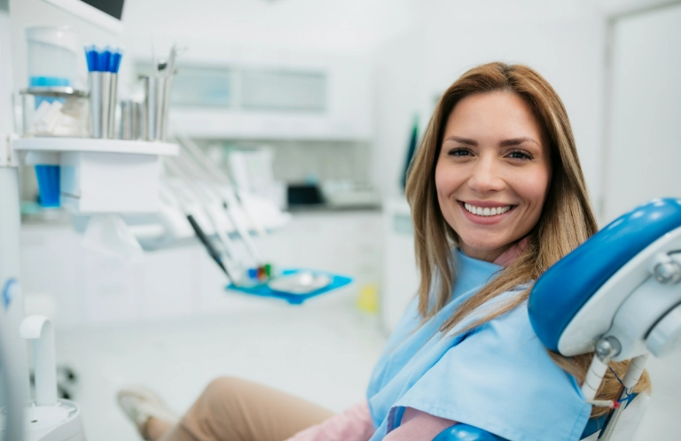 Uśmiechnięta kobieta na&nbsp;fotelu stomatologicznym